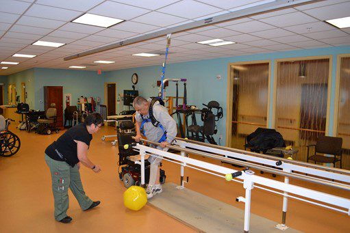 man using parallel bars in physical therapy