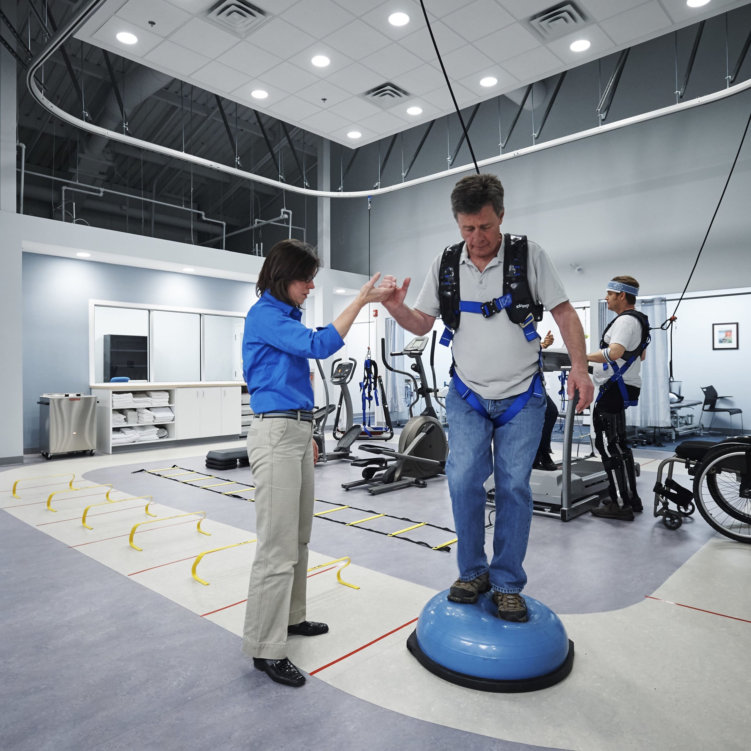 Man standing on the Bosu ball in a facility with a solo step track