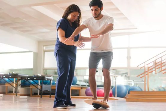 Physical therapist helping patient use a balance board