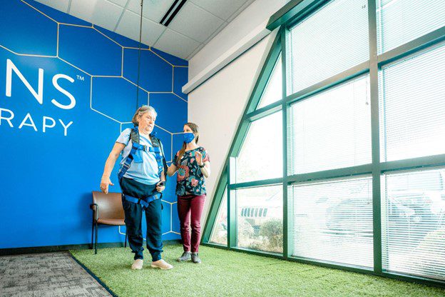 A patient using a solo-step harness and physical therapist stand together