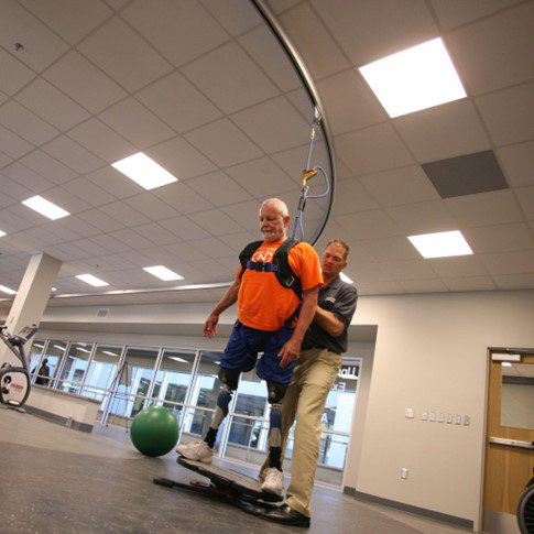 A man with prosthetic legs practices on a balance board