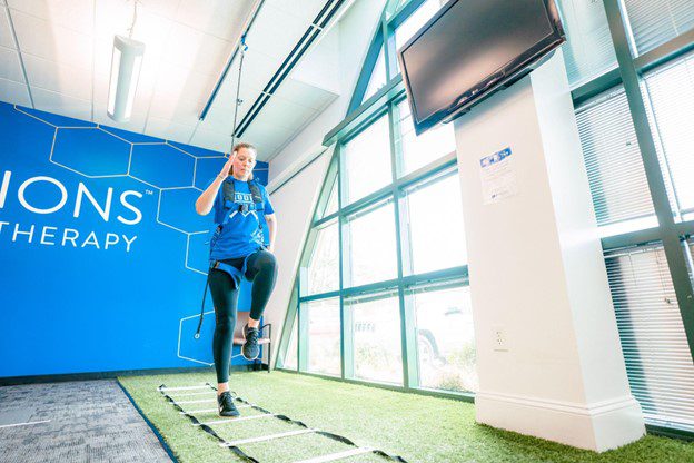 A woman running through an obstacle on indoor turf