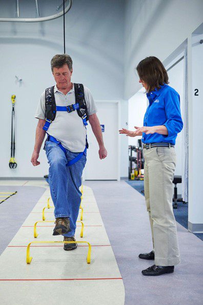 A man walks through obstacles while his physical therapist supervises