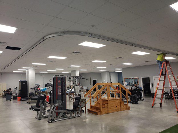 An "L" shaped track being installed into a large physical therapy room
