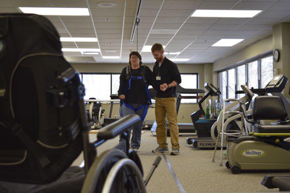 A spinal patient walks with assistance from a physical therapist